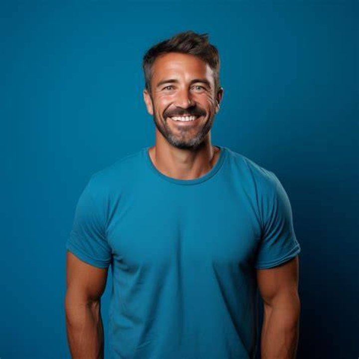 a man wearing a blue shirt with a necklace on his neck is looking at
